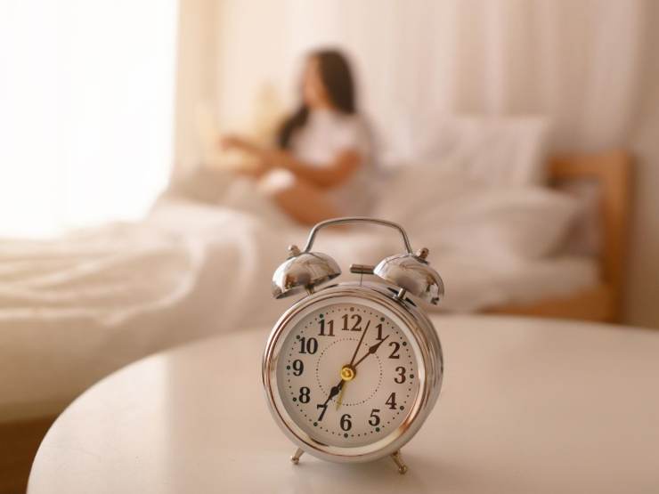 Sveglia in primo piano e persona che dorme